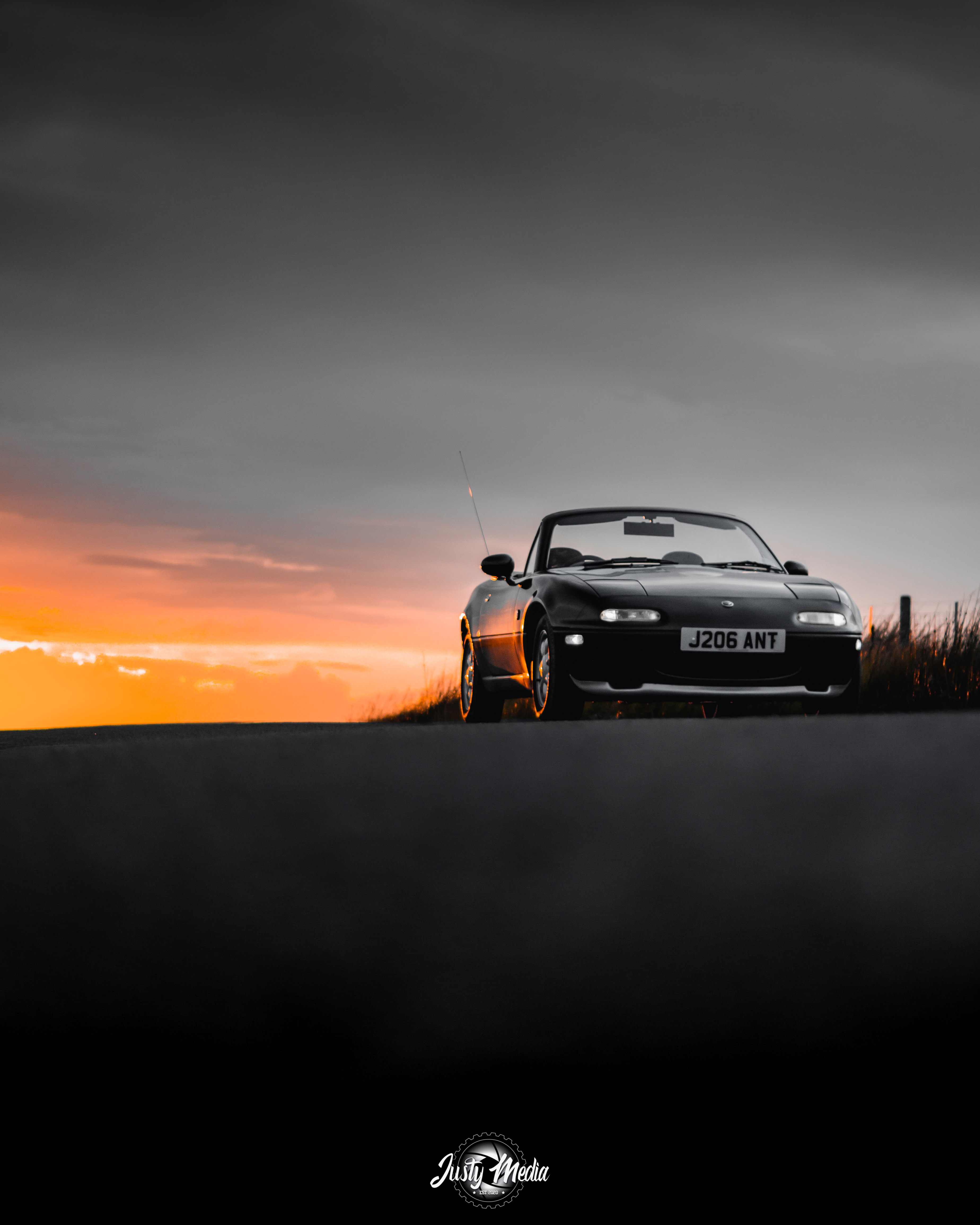 Black Mazda MX-5 photographed at sunset