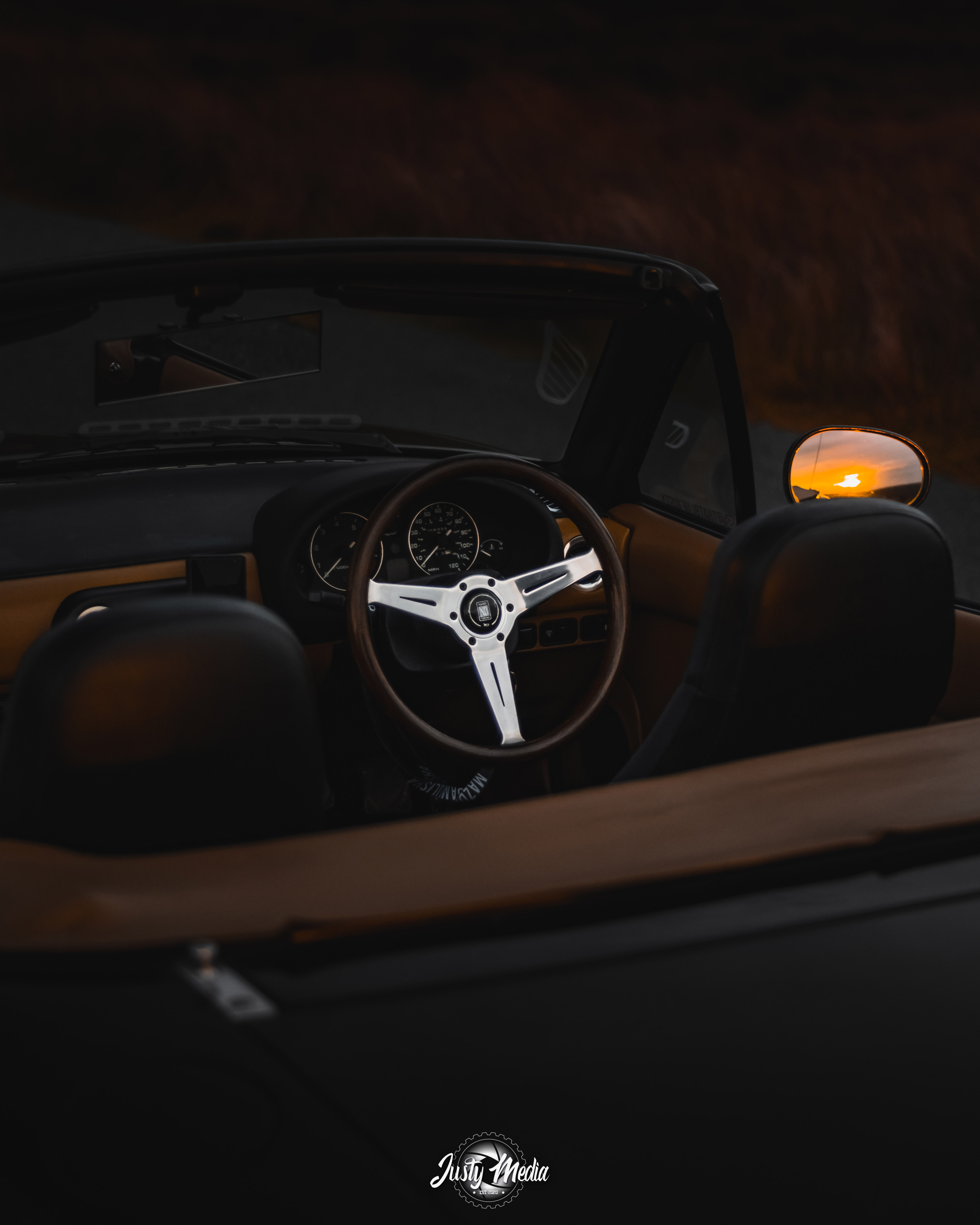 Interior of a Mazda MX-5 with sunset reflection in the mirror